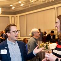 Andrew Bixel chatting with woman at event